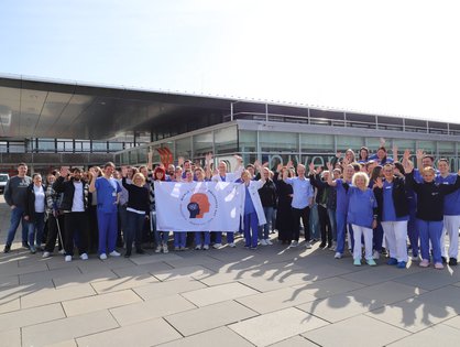 Vor dem Haupteingang des Universitätsklinikums Ulm: Mitarbeitende setzen am Weltdelirtag mit der Delirflagge ein Zeichen für mehr Aufmerksamkeit für das Krankheitsbild. (Foto: Universitätsklinikum Ulm)